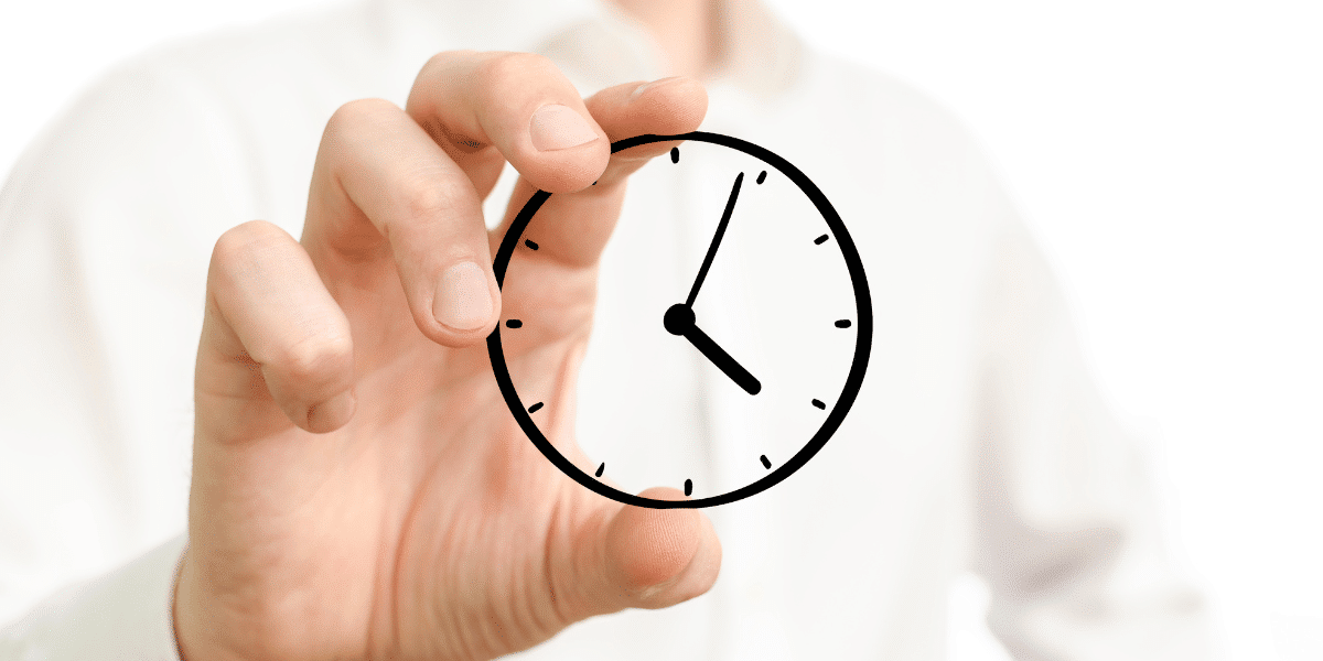A person holding a small, round piece of glass with an analog clock face drawn on it to represent the time agents spend working on real estate transactions.
