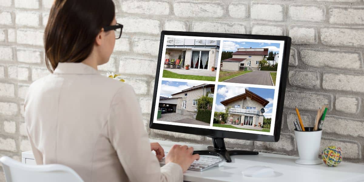 Woman looking at property listings on a computer screen with four house images.