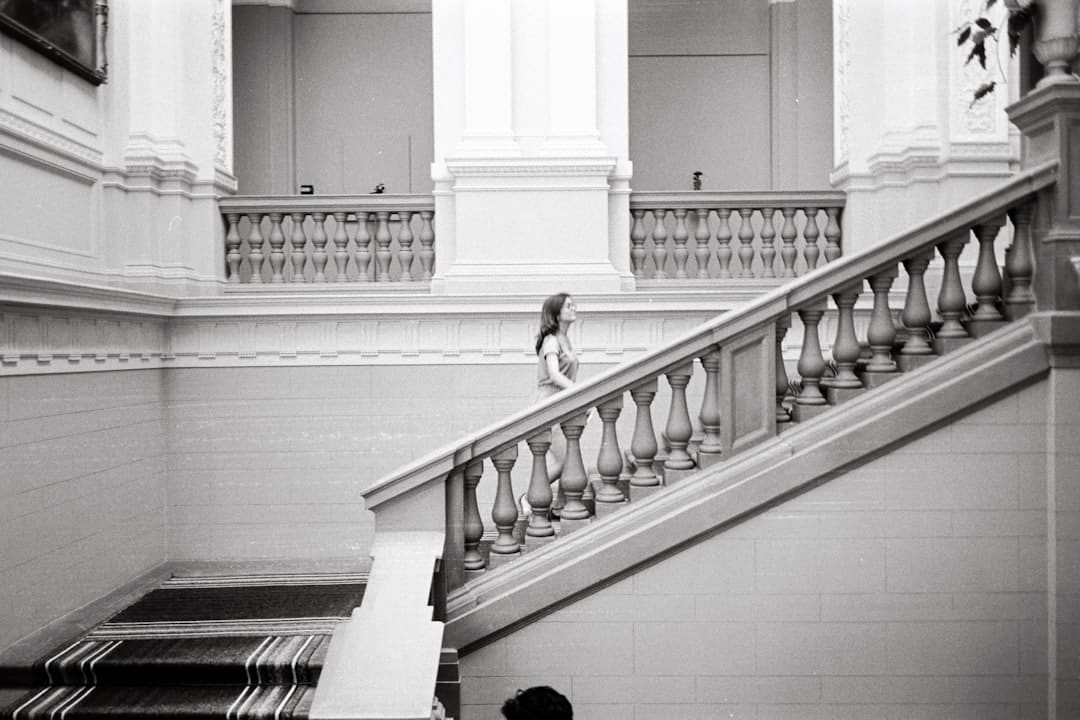 A person viewed from a low angle, confidently walking up a minimalist, modern staircase, symbolizing career progression and moving to the next level.