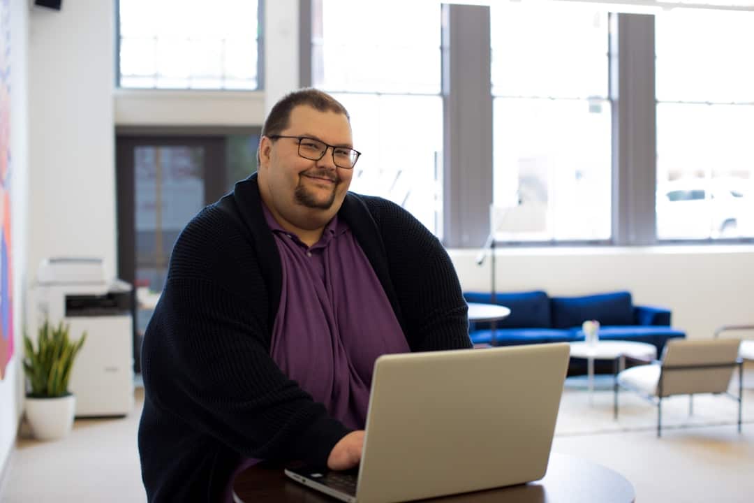 A professional real estate agent works efficiently on a laptop in a bright, modern, and minimalist office, symbolizing a streamlined and profitable business model.