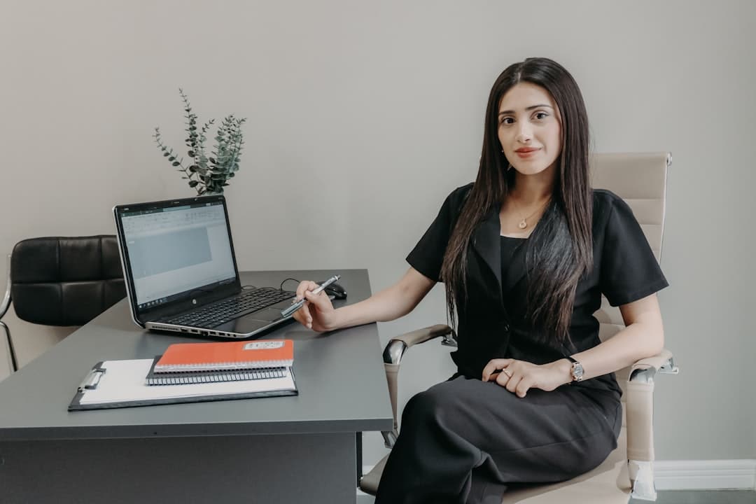 A real estate agent with a thoughtful expression looks out the window of a sleek, modern office, contemplating the challenges and future of their career.