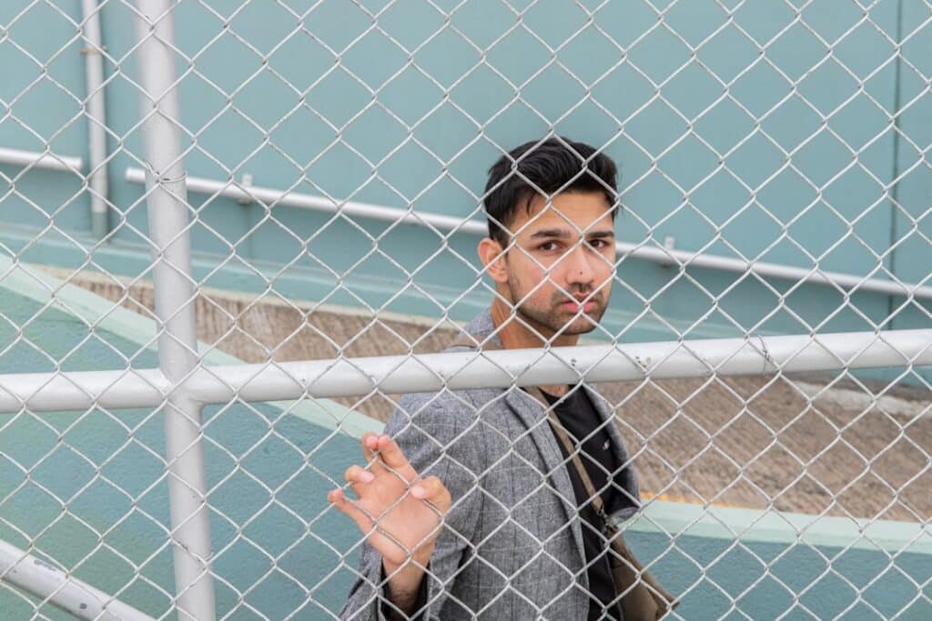 Well-dressed real estate agent decisively opens a large, modern gate, symbolizing smashing barriers to brokerage ownership.