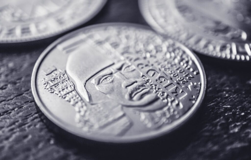 Well-dressed real estate agent looks down with a frustrated expression at a few coins in their open palm, symbolizing the ...