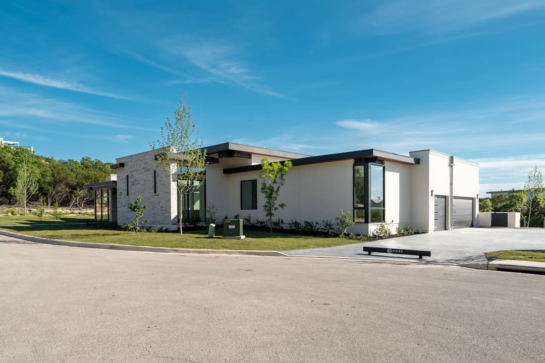 The bright, sunny exterior of a modern, minimalist home, representing a successful real estate listing with a contemporary brokerage.