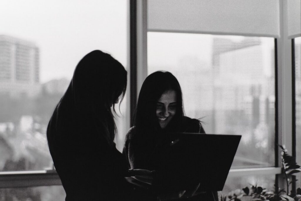 Diverse group of real estate agents in a forced, overly enthusiastic huddle inside a bright, modern office, symbolizing th...