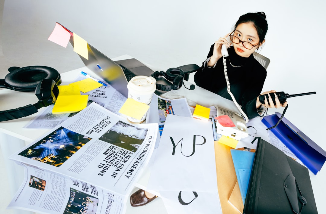 A real estate agent sits at a desk looking worriedly at a calculator and a pile of bills, representing the financial pressure of high commission splits and fees.