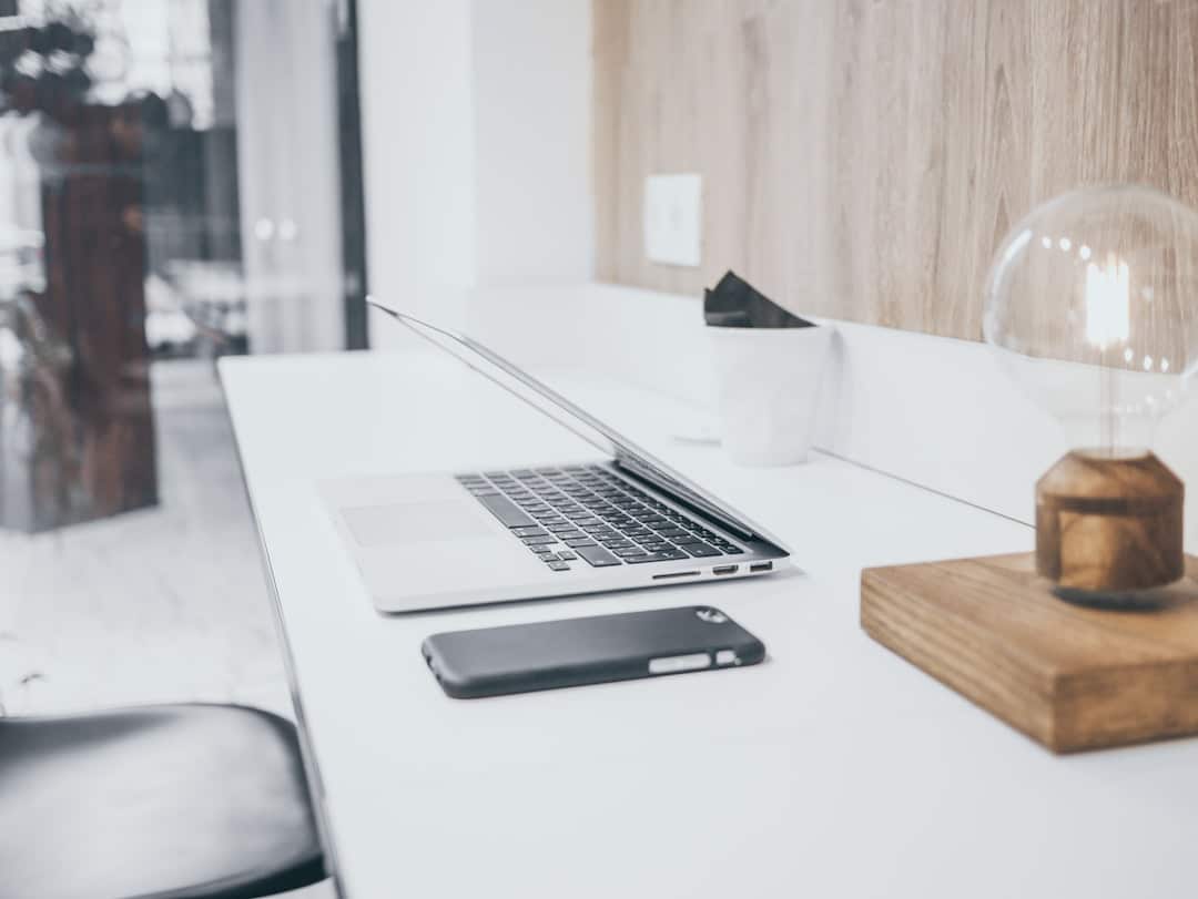 A set of modern house keys lies on a sleek business desk next to a laptop, symbolizing the opportunity of franchise ownership in real estate.