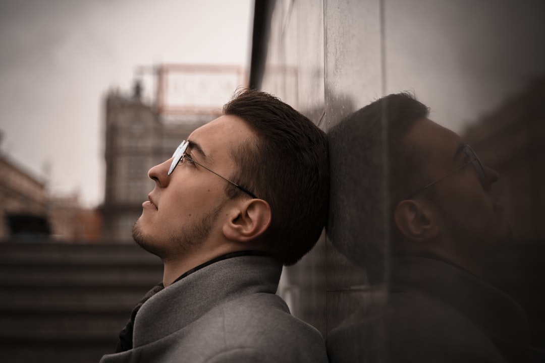 A top-producing real estate agent looks out the window of a luxury high-rise, appearing pensive and trapped despite their financial success.