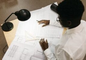 Clean architectural blueprint laid out on a modern white desk, symbolizing a well-designed business plan for a lean real e...