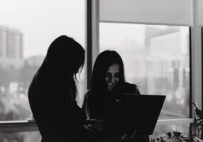 Diverse group of real estate agents in a forced, overly enthusiastic huddle inside a bright, modern office, symbolizing th...