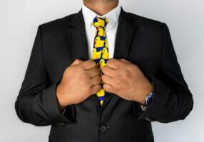 Real estate agent in a sharp business suit with their hands bound by golden handcuffs, symbolizing the restrictive nature ...