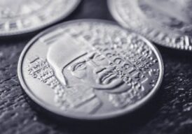 Well-dressed real estate agent looks down with a frustrated expression at a few coins in their open palm, symbolizing the ...